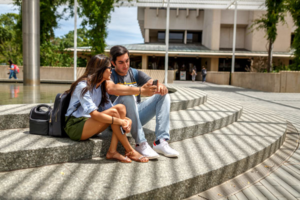 UT Dallas students looking a the Jindal School website on a smartphone