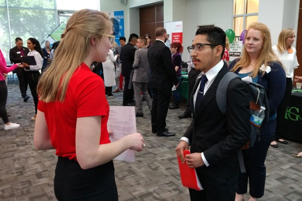 Jindal School student researching employers face-to-face at a career fair