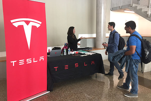students talking with a recruiter at a Tesla recruiting table at the Jindal School of Management