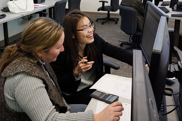 A UT Dallas JSOM Finance Lab team member works with a student on a project.