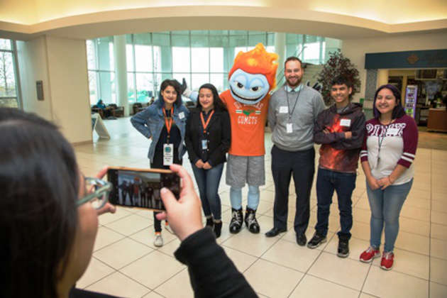 Student takes cell phone photo of UT Dallas mascot Temoc and Moises E. Molina students and faculty.