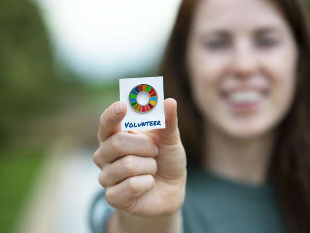 Student holds up a badge that says, Volunteer.