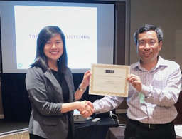 Claudia Kwee and Dr. Thanh Tran shake hands as Claudia holds her award.