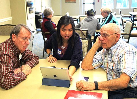 Community member Bob O'Steen and student Jermaine Phua gather around an iPad.
