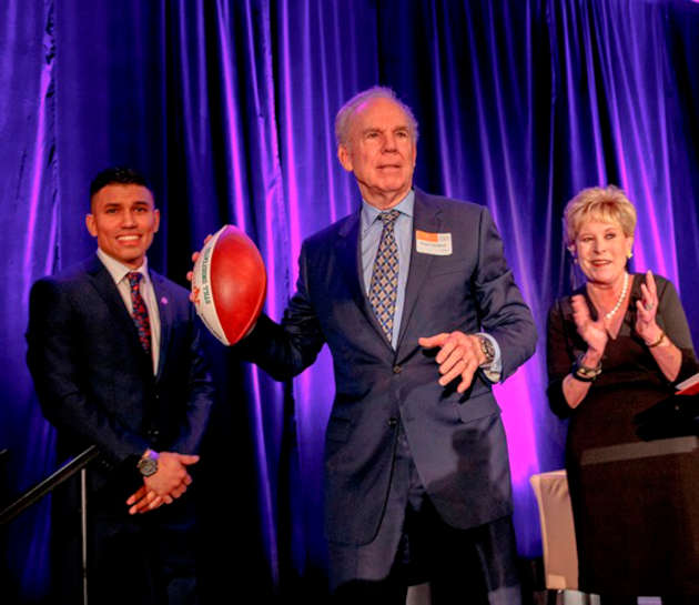 After being presented with a “Still Undefeated” UT Dallas commemorative football by Giovanny Martinez (left) and JSOM Associate Dean Diane McNulty (right), moderator Roger Staubach delighted the audience by pretending to throw a pass.