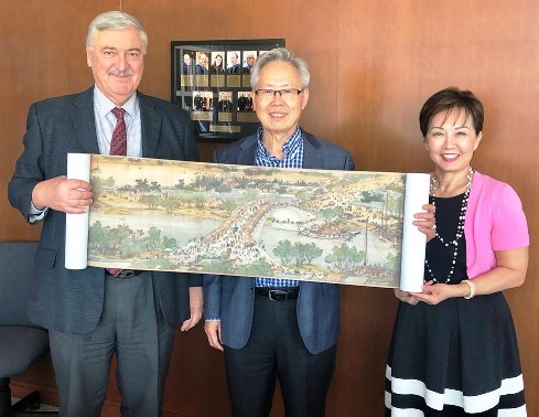 Hasan Pirkul, Charlie W. Chen, and Pauline Chen holding a reproduction of the Chinese scroll Spring Festival Along the River