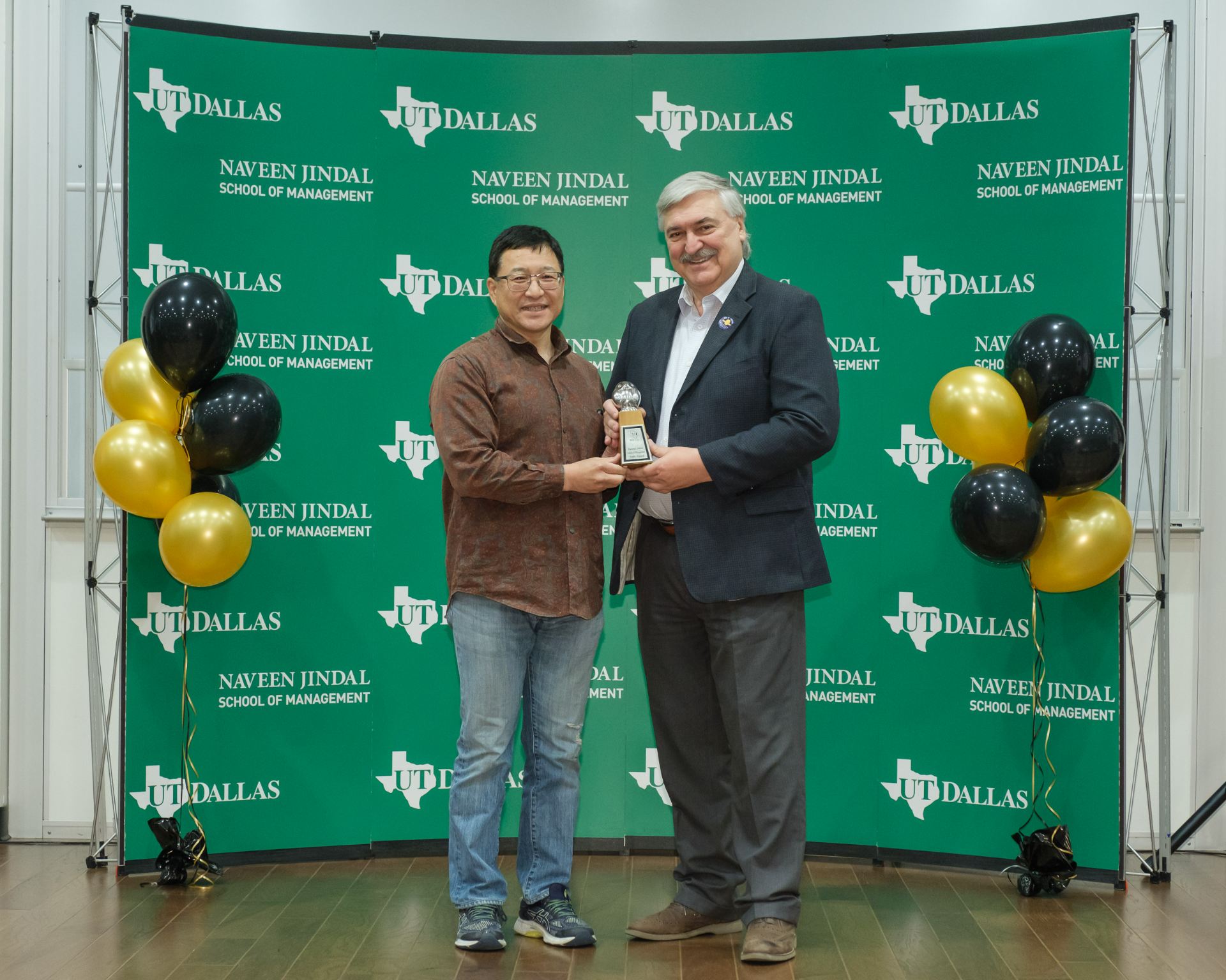 Dr. Riki Takuchi accepts 2023 Owlie Award for Faculty of the Year from Dean Hasan Pirkul