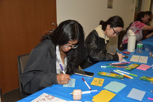 Photo of JSOM students filling out inspirational cards for the Stewpot artists
