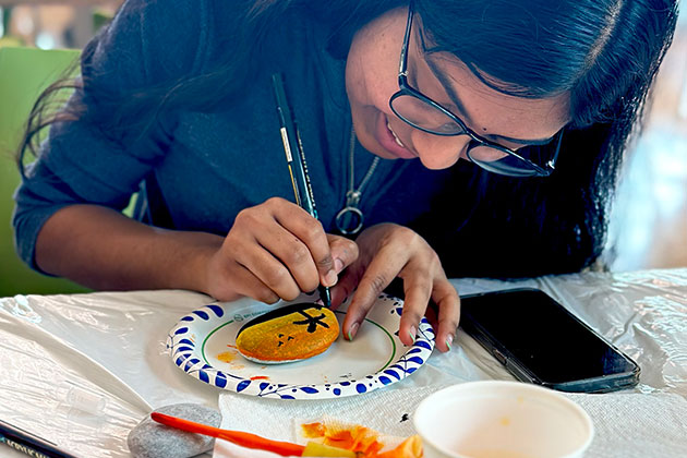 JSOM student paints a rock for Stress Less With JSOM before exam week.