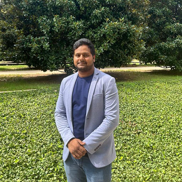 MS in Supply Chain Management student Abinav Bayya stands outside UT Dallas with the magnolia trees.